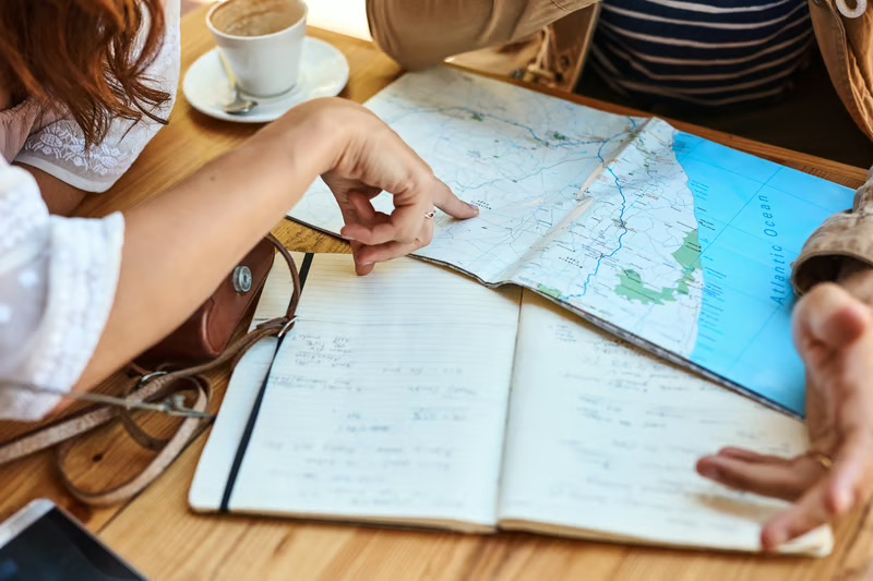 Travelers reviewing a map and itinerary while planning an international trip.